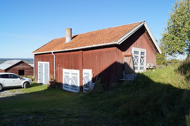 Vamsta 5:3. Ladugård i röd panel med två blå dubbelportar med vitt kryss, och blå dubbelport.