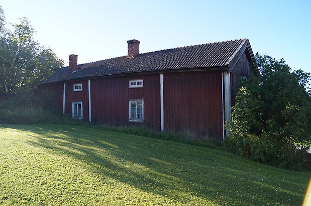 Åkre 1:5. Byggnad i två våningar i röd panel med vita detaljer, fönster med vita spröjs, två skorstenar i tegel.