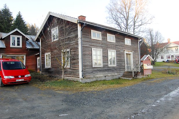 Lockne-Berge 1:2. Hus i grå, liggande panel i två våningar, fönster med vita spröjs, en liten trapp upp till en grå dubbeldörr.