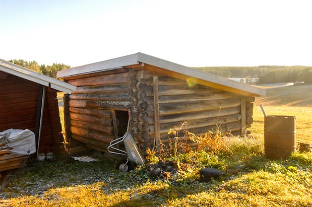 Lockne-Berge 1:7. Timrad, grå byggnad med öppen lucka och sluttande tak.