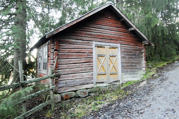 Lockne-Berge 2:2. Byggnad i brunt timmer med trasiga fönster med spröjs och gul dubbelport.