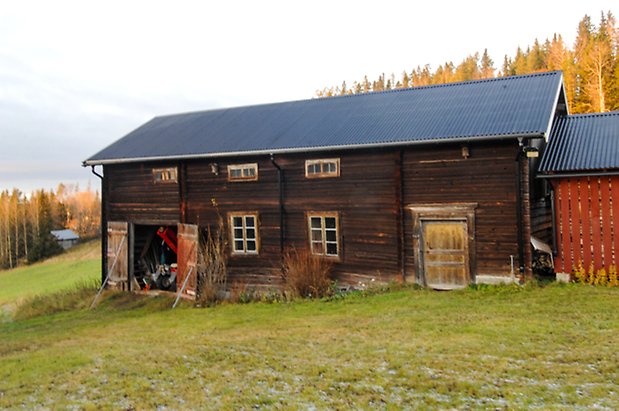 Börön 1:2. Byggnad i svart timmer, dubbelport och gul dörr och fönster med spröjs.