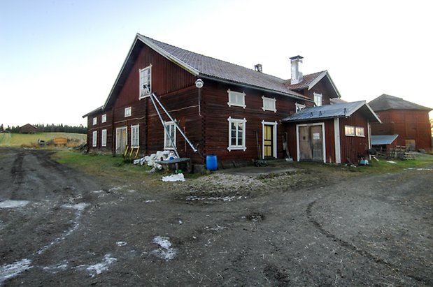 Börön 4:1. Timrad ladugård i brunt timmer och panel i tre våningar, med gul dubbelport och dörr i gult och rött, fönster med vita spröjs.