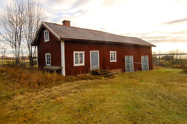 Ångsta 2:2. Byggnad i två våningar, i röd panel med två blå dubbelportar, blå dörr och fönster med vita spröjs.