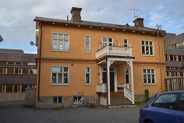 Stenhus i två våningar i gul puts, vita fönster med spröjs. Vit förstukvist med balkong ovanför. Två skorstenar i tegel.