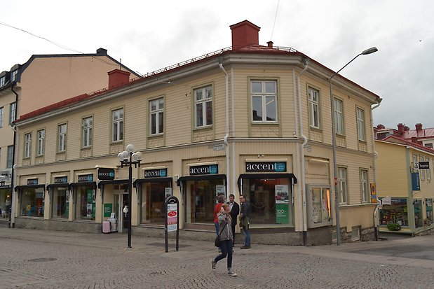 Trähus i två våningar i ljusgul liggande panel. Vita knutar, fönster och spröjs. Ljusgröna fönsterfoder och detaljer. Rött plåttak med två skortstenar. Skyltfönster på nedervåningen.