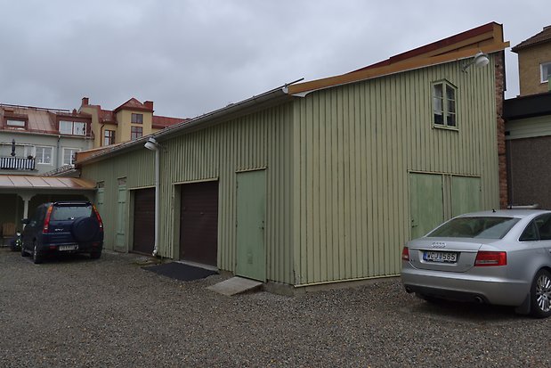 Byggnad med snetak, grön panel, grönt fönster med spröjs, gröna dörrar och två bruna garageportar.
