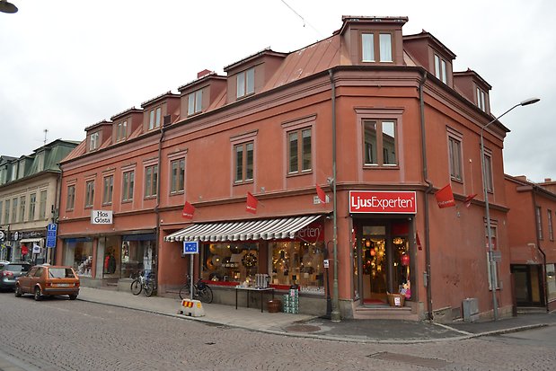 Trevånings hus i röd puts med ljusröda detaljer och rött plåttak med takkupor. 