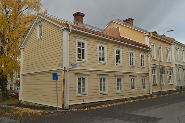 Gult hus i två våningar med liggande panel och vita fönster med vita spröjs.