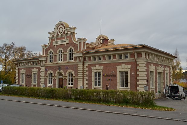 Tegelbyggnad i två våningar, knutar, detaljer och fönster i vit sten.