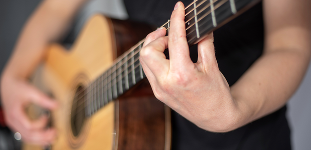 Närbild på någon som spelar gitarr