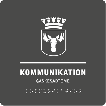 Mörkgrå skylt med kommunvapnet i vitt, ett avskiljande vitt streck samt texten "Kommunikation" i vitt på både svenska och sydsamiska.