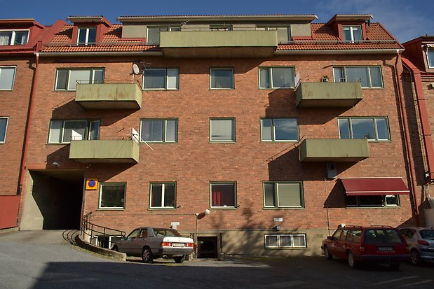Bostadshus i rött tegel med gröna balkonger. 