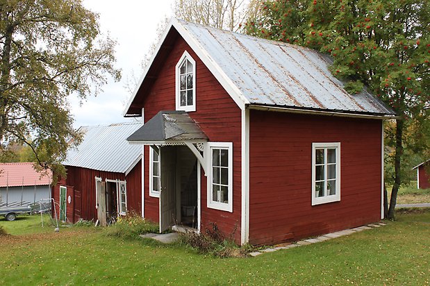 Spinetten 1. Hus med röd, liggande panel och vita fönster med spröjs, plåttak. 