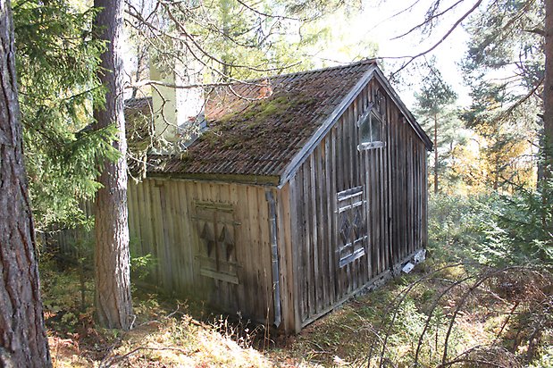 Valla 8:15. Hus, omålad, åldrad panel. Utsmyckade fönsterluckor och skorsten med vit puts.