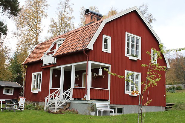 Pianot 3. Villa i röd panel, vita fönster med spöjs, rött tegeltak med balkong.