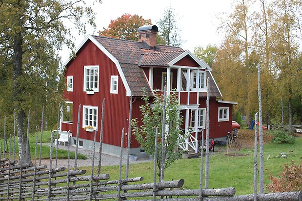 Pianot 3. Villa i röd panel, vita fönster med spöjs, rött tegeltak med balkong.