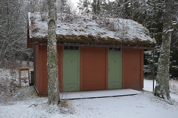 Valla 6:43. Byggnad i brun liggande panel och två gröna dörrar.