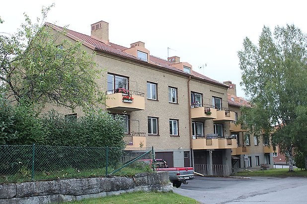 Söre 2:98. Flerbostadshus i fyra våningar i gult tegel med gula balkonger, bottenvåningen har lokaler.