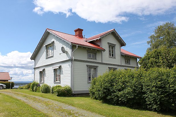 Orrviken 5:1. Villa i vit liggande panel med grå fönster med vita spröjs.Rött tak.