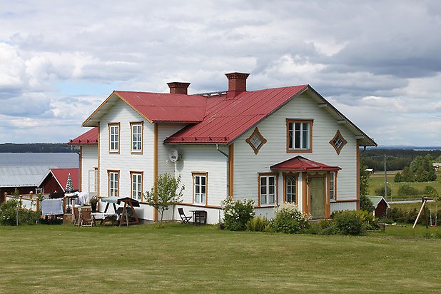 Orrviken 6:1. Villa i vit liggande panel med gula detaljer och vita fönster med spröjs. Rött plåttak.