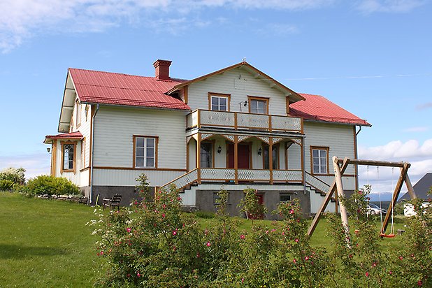 Orrviken 6:1. Villa i vit liggande panel med gula detaljer och vita fönster med spröjs. Rött plåttak. Förstukvist och balkong.