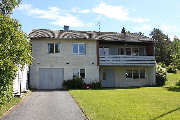 Orrviken 6:28. Villa i grå puts med vita fönster och grå garageportar och grå dörr.