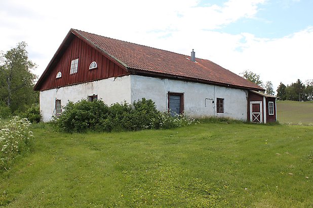 Sunne-Gärde 2:20. Byggnad med övervåning i röd panel och undervåning i vit puts, små fönster och blå dörr.