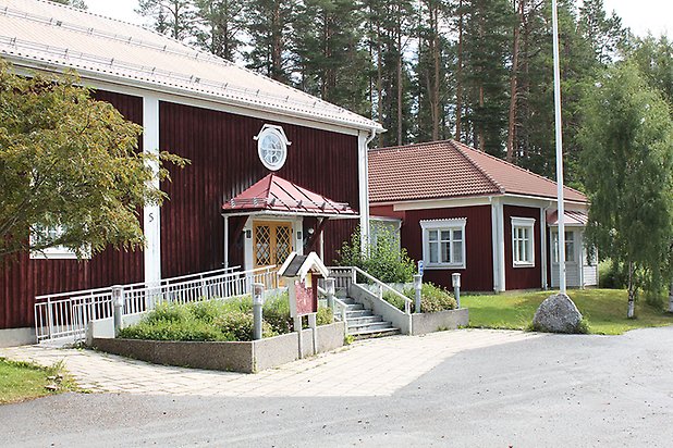 Tand 2:66. Byggnad i röd panel med vita fönster med spröjs, gul dubbeldörr med runt vitt fönster ovanför.