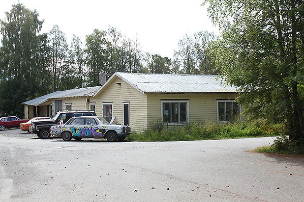 Tand 2:82. Byggnad i ljusgul, liggande panel med vita fönster.