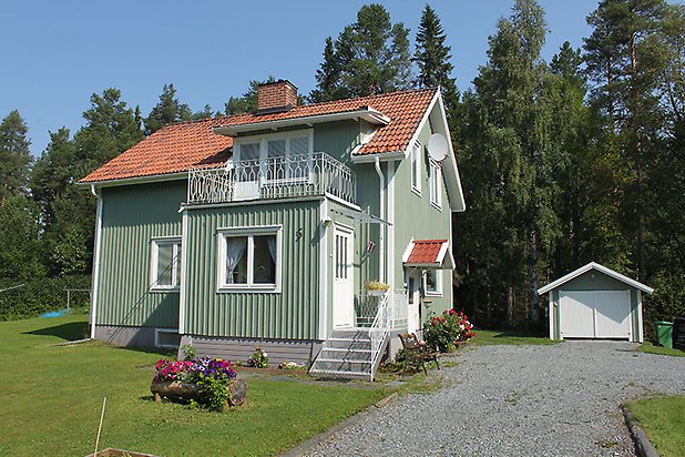 Tand 2:9. Villa i grön panel med vita fönster, balkong i vitt smide och rött tegeltak.