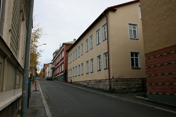 Byggnad i sten i ljusgul puts med vita detaljer, vita fönster med spröjs och grund i sten.