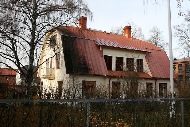 Stenvilla i tre våningar i ljusgul puts, rött plåttak med tegelskorstenar.  Röda fönster med spröjs. Balkong på kortsidan.